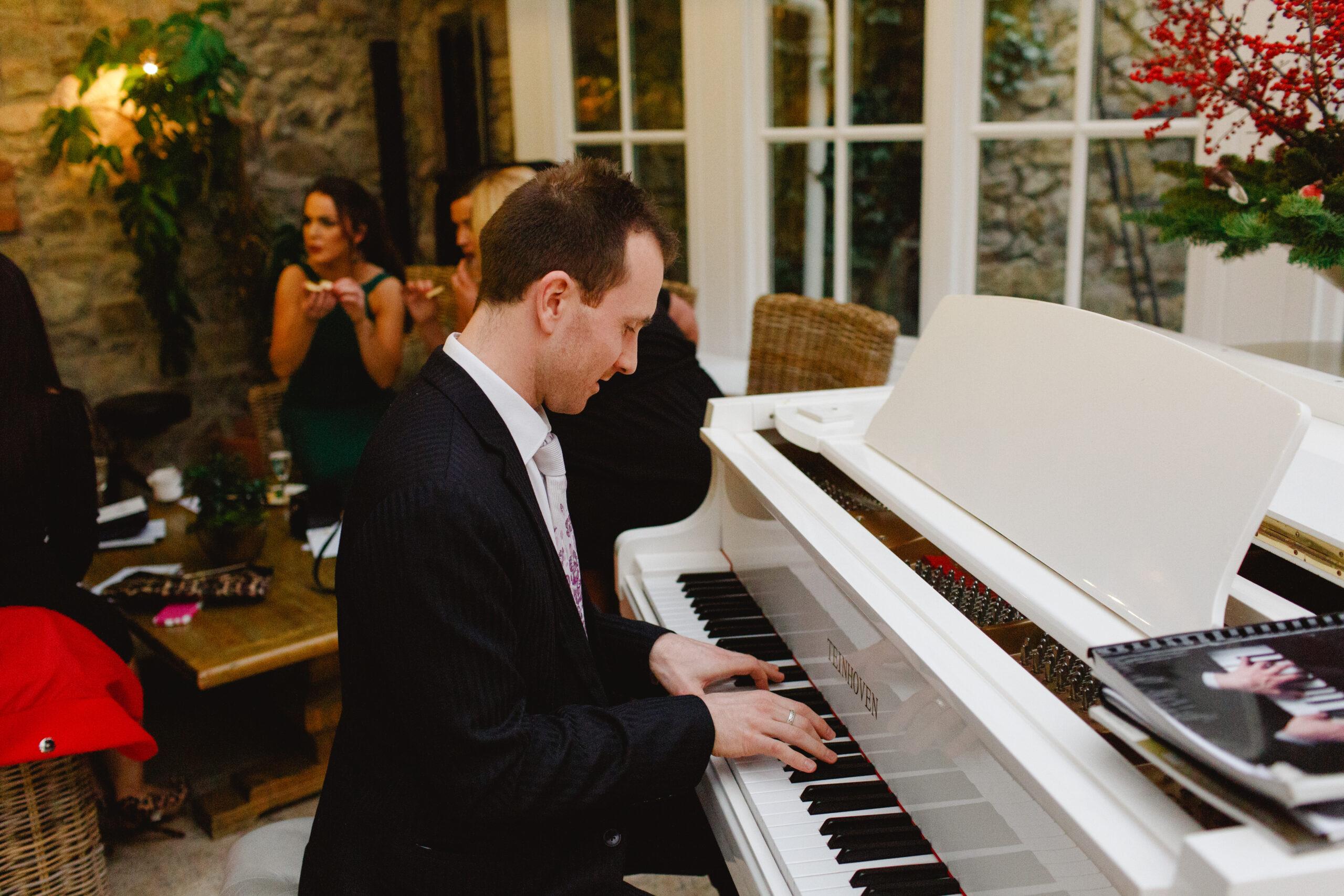 Joe Kenny playing on a white baby grand piano at a wedding drinks reception in Ballymagarvey Village, Co. Meath